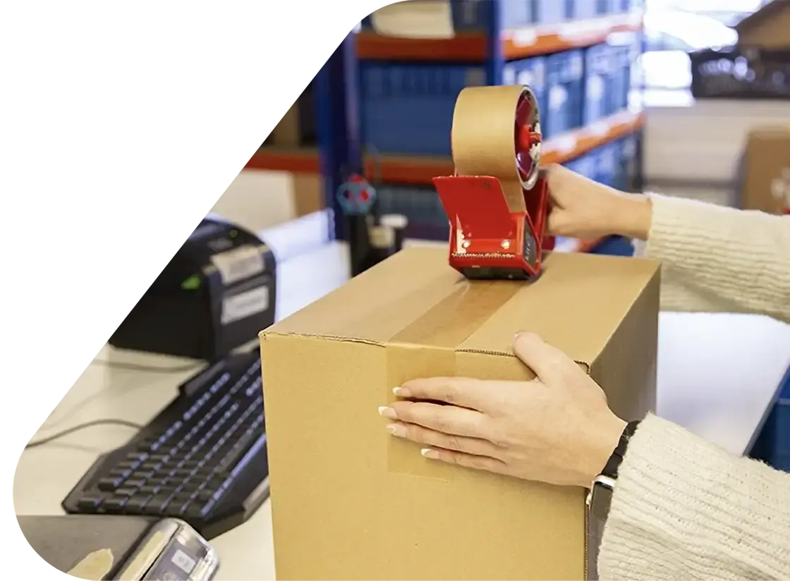 Person-taping-a-box-with-paper-tape-in-a-warehouse