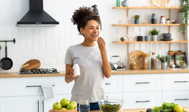 Smiling woman taking supplements in her kitchen