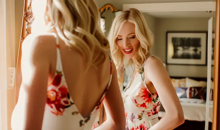 a women trying on a floral dress in a sunlit bedroom