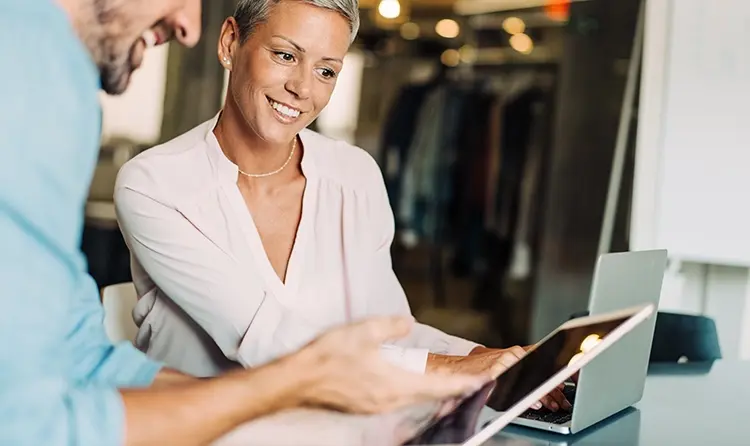 a man and a woman discuss something looking at a tablet 