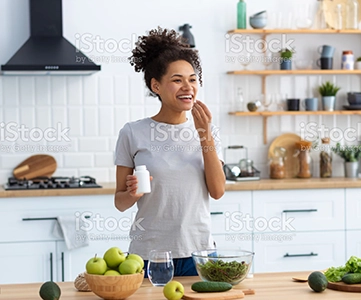 Smiling woman taking supplements in her kitchen 1 |