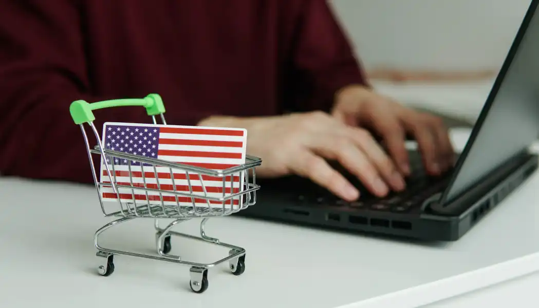 A Person Working On A Laptop with A Small Shopping Trolley with An American Flag